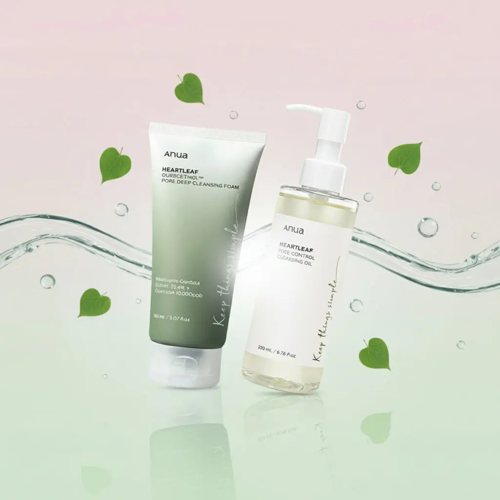 Deux produits de la marque Anua sont présentés côte à côte sur un fond dégradé rose et vert pastel, entourés de feuilles de cœur et de gouttelettes d’eau. À gauche se trouve un tube vert de mousse nettoyante, et à droite un flacon pompe transparent d’huile démaquillante, tous deux avec la mention “Keep things simple” sur l’emballage.