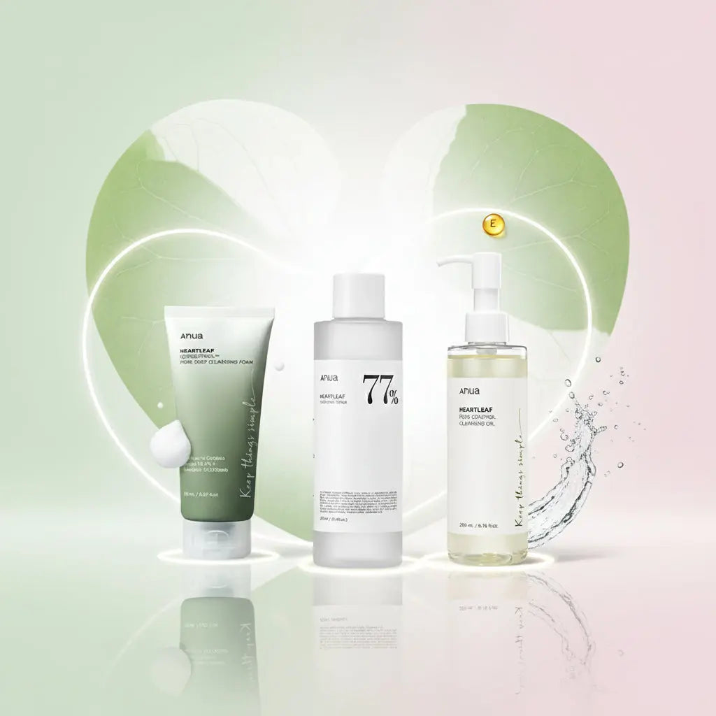 Trois produits de la marque Anua sont alignés devant deux grandes feuilles de cœur lumineuses : à gauche, un tube de mousse nettoyante avec une petite boule de mousse, au centre une bouteille de toner Heartleaf 77%, et à droite un flacon pompe d’huile démaquillante. Des effets d’eau et une capsule de vitamine E ajoutent une touche fraîche et naturelle à la scène sur fond dégradé vert et rose.